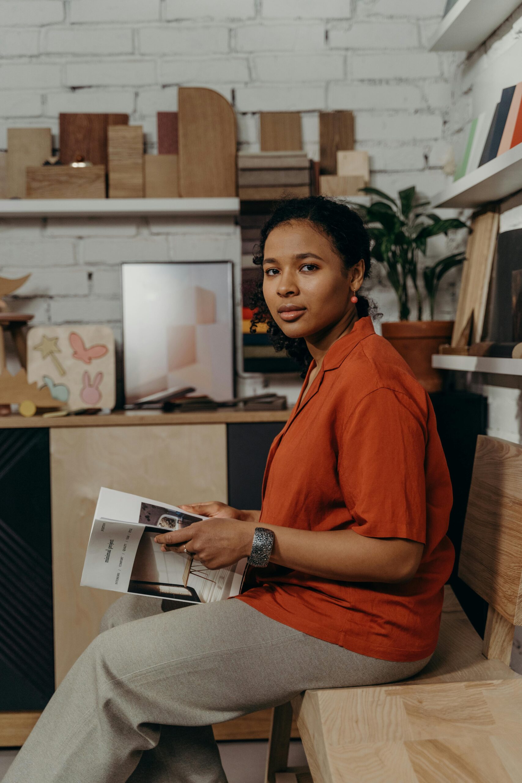 Black woman sitting in a furniture showroom, reviewing catalogs with various material samples.